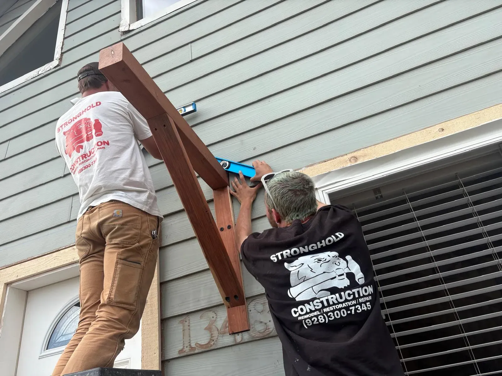 Two Stronghold crew members leveling a cedar bracket above a window on a Flagstaff home