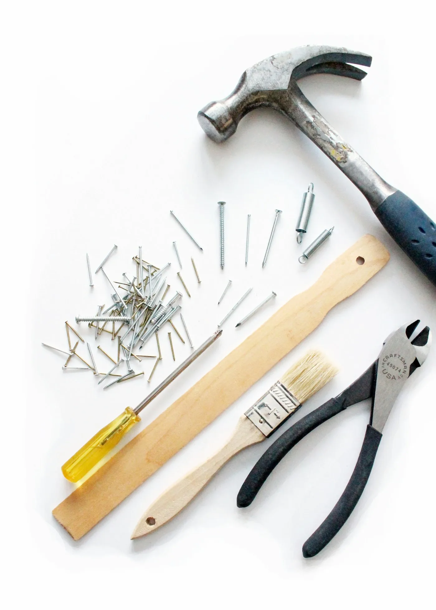 Handyman tools laid out: hammer, screwdriver, nails, and pliers